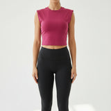 Pink sleeveless top on a hanger with beige pants in the background.
