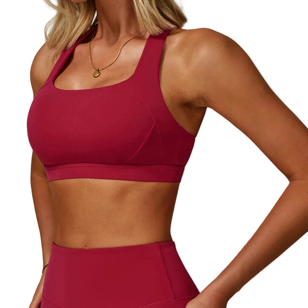 Woman wearing a red sports bra and leggings on a plain background