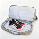 Open beige shoe storage bag with colorful sneakers inside on a light gray background