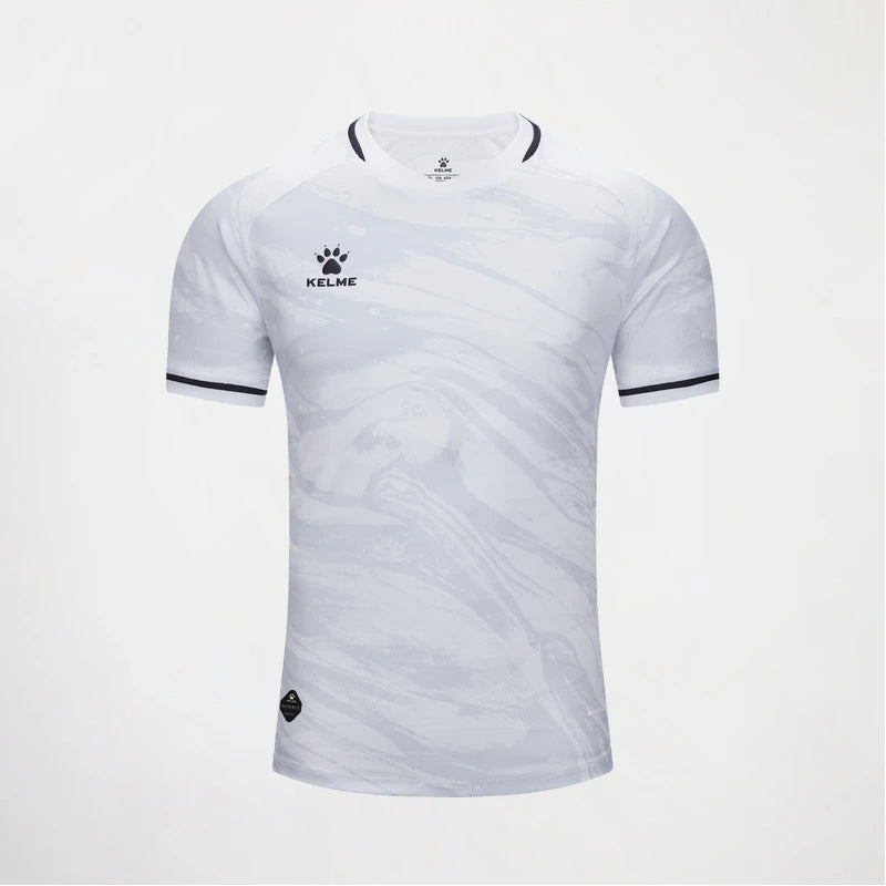 A white short-sleeve athletic jersey with a subtle gray marbled pattern, featuring a black KELME logo on the left chest and black trim on the collar and sleeve cuffs, displayed against a light gray background.