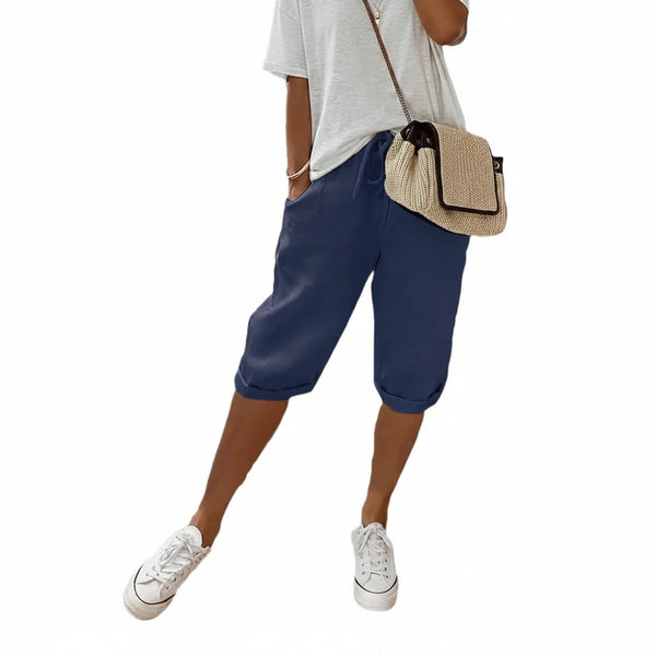 Person wearing blue shorts, white sneakers, and a beige bag on a white background