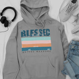 Gray hoodie with 'Blessed Beyond Measure' text, headphones, sneakers, and jeans on a white background